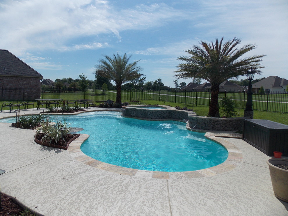 Ejemplo de piscinas y jacuzzis naturales tropicales grandes tipo riñón en patio trasero con adoquines de piedra natural