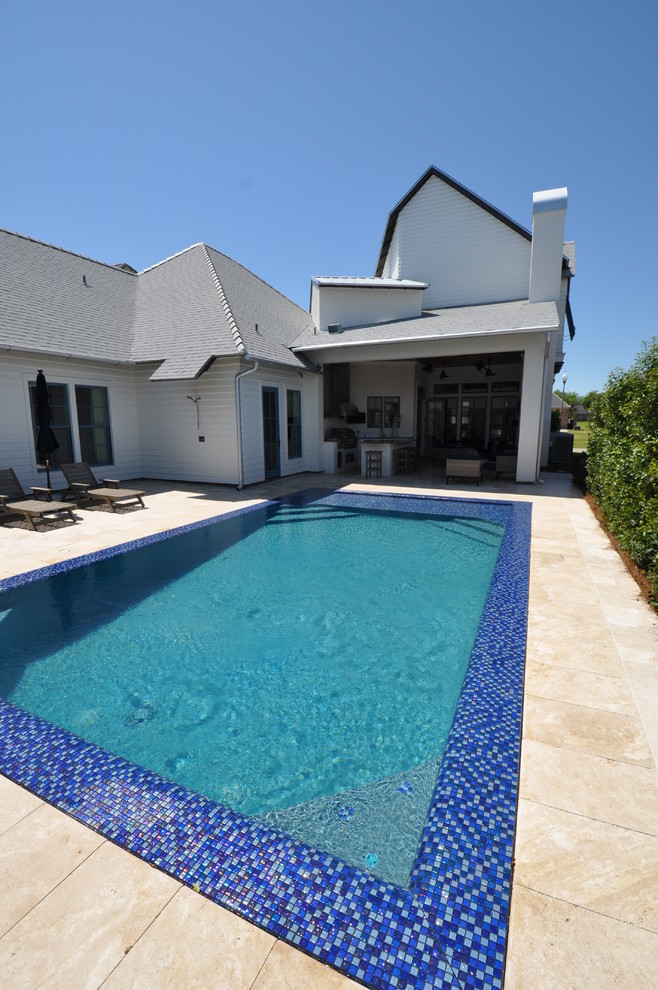 Ejemplo de piscina alargada de estilo americano de tamaño medio rectangular en patio trasero con suelo de baldosas