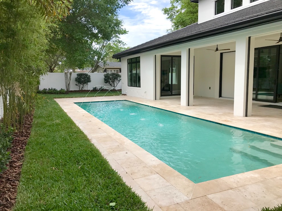 Пример оригинального дизайна: прямоугольный бассейн на заднем дворе в современном стиле с покрытием из каменной брусчатки