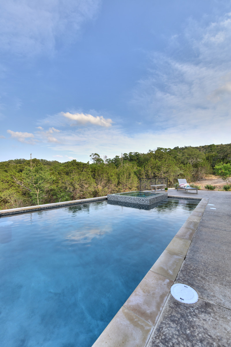 Immagine di una grande piscina classica rettangolare dietro casa con una vasca idromassaggio e pavimentazioni in cemento
