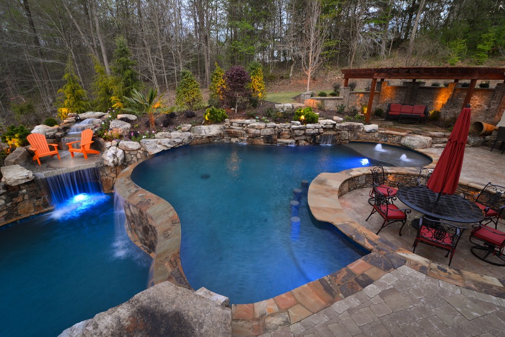 Esempio di un'ampia piscina stile rurale personalizzata dietro casa con pavimentazioni in pietra naturale