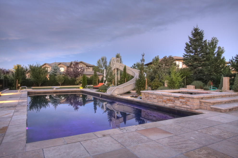 Esempio di una grande piscina monocorsia tradizionale rettangolare dietro casa con un acquascivolo e pavimentazioni in pietra naturale
