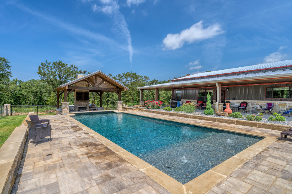 Imagen de piscina clásica de tamaño medio rectangular en patio delantero con adoquines de hormigón