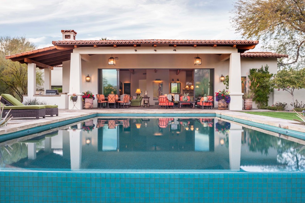 Immagine di una grande piscina a sfioro infinito mediterranea rettangolare dietro casa con pavimentazioni in pietra naturale