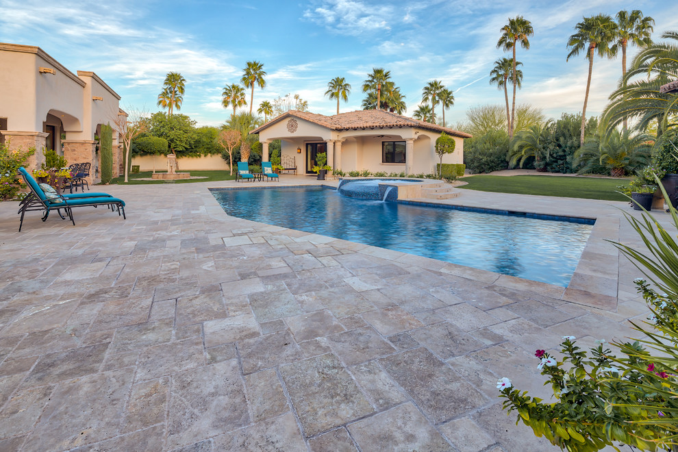 This is an example of a large contemporary back custom shaped swimming pool in Phoenix with concrete paving.