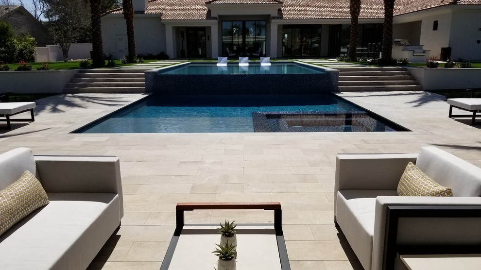Immagine di una grande piscina monocorsia minimal rettangolare dietro casa con una dépendance a bordo piscina e pavimentazioni in pietra naturale