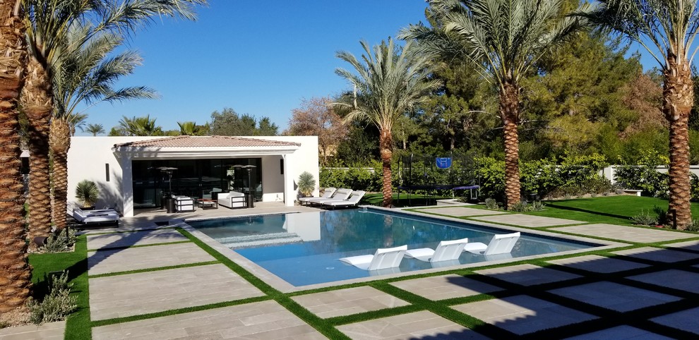 Стильный дизайн: большой прямоугольный, спортивный бассейн на заднем дворе в современном стиле с домиком у бассейна и покрытием из каменной брусчатки - последний тренд
