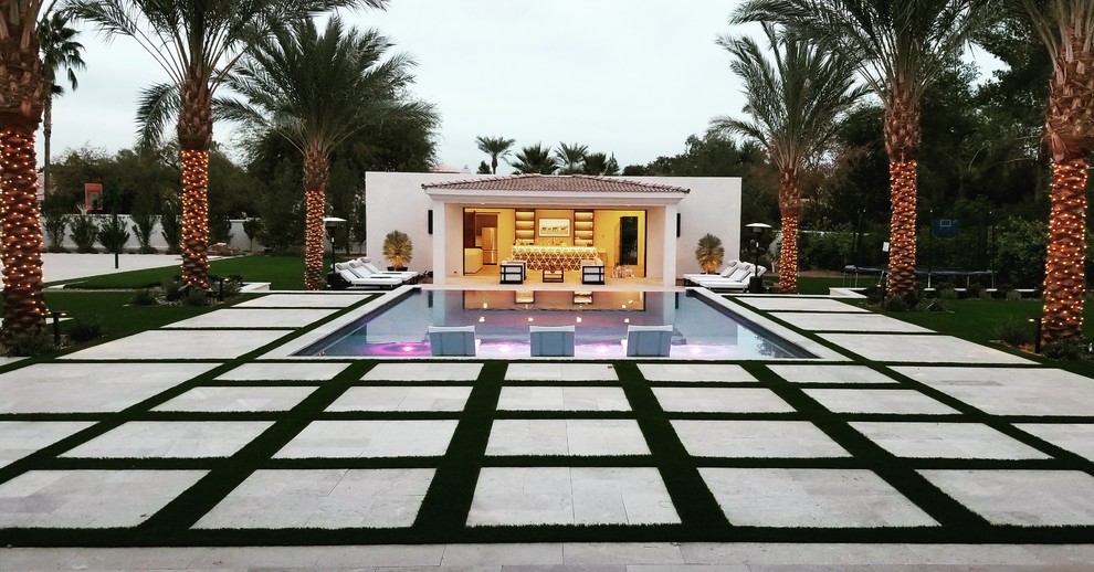 Ejemplo de casa de la piscina y piscina alargada actual grande rectangular en patio trasero con adoquines de piedra natural
