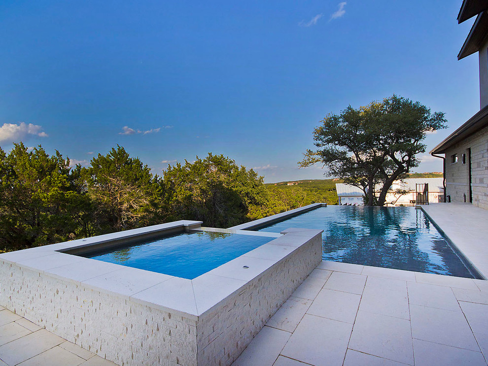 Modelo de piscinas y jacuzzis infinitos, contemporáneos, de tamaño medio, rectangulares, en patio trasero, con adoquines de piedra natural