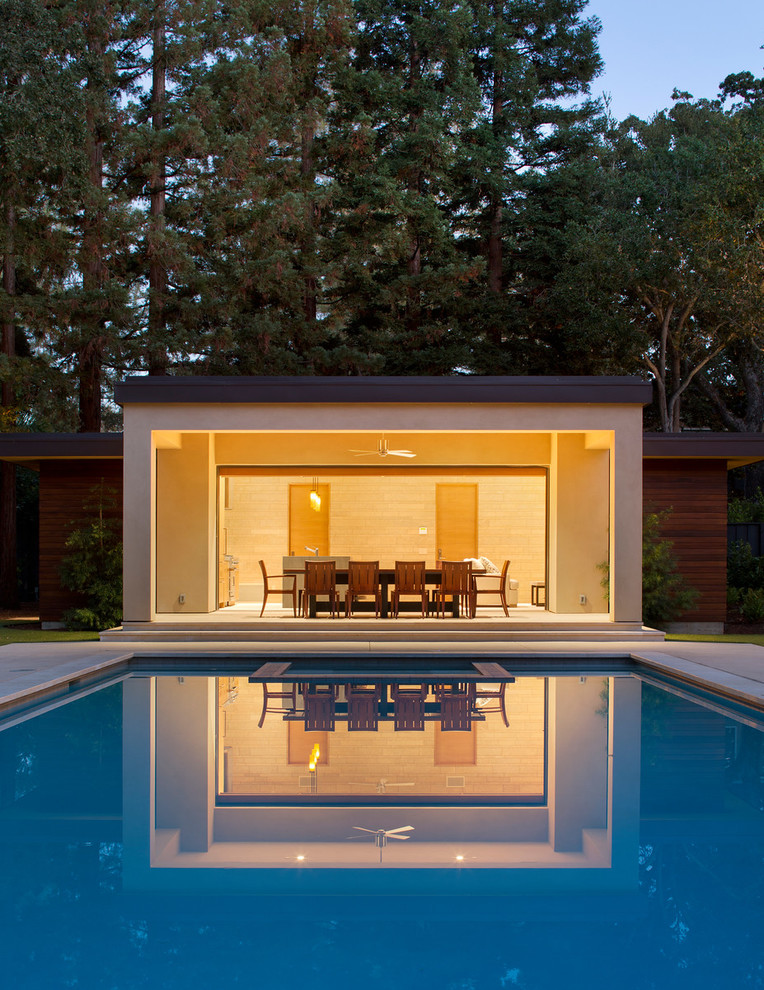 Modelo de casa de la piscina y piscina alargada minimalista grande rectangular en patio trasero con suelo de hormigón estampado