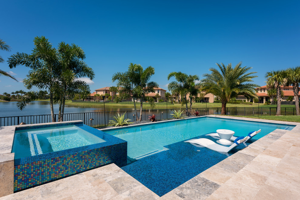 Esempio di una grande piscina a sfioro infinito minimalista personalizzata dietro casa con una vasca idromassaggio e pavimentazioni in pietra naturale