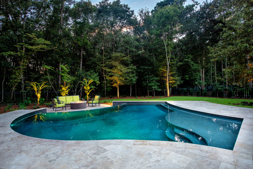 Ejemplo de piscina infinita clásica renovada de tamaño medio a medida en patio trasero con adoquines de piedra natural