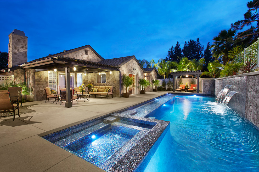 Ejemplo de piscina con fuente alargada contemporánea de tamaño medio rectangular en patio trasero con suelo de hormigón estampado