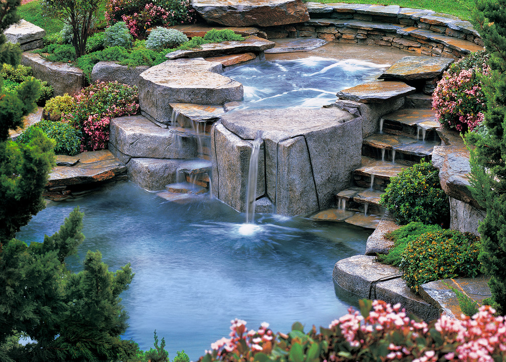 Immagine di una piscina naturale etnica personalizzata di medie dimensioni e dietro casa con fontane e pavimentazioni in pietra naturale