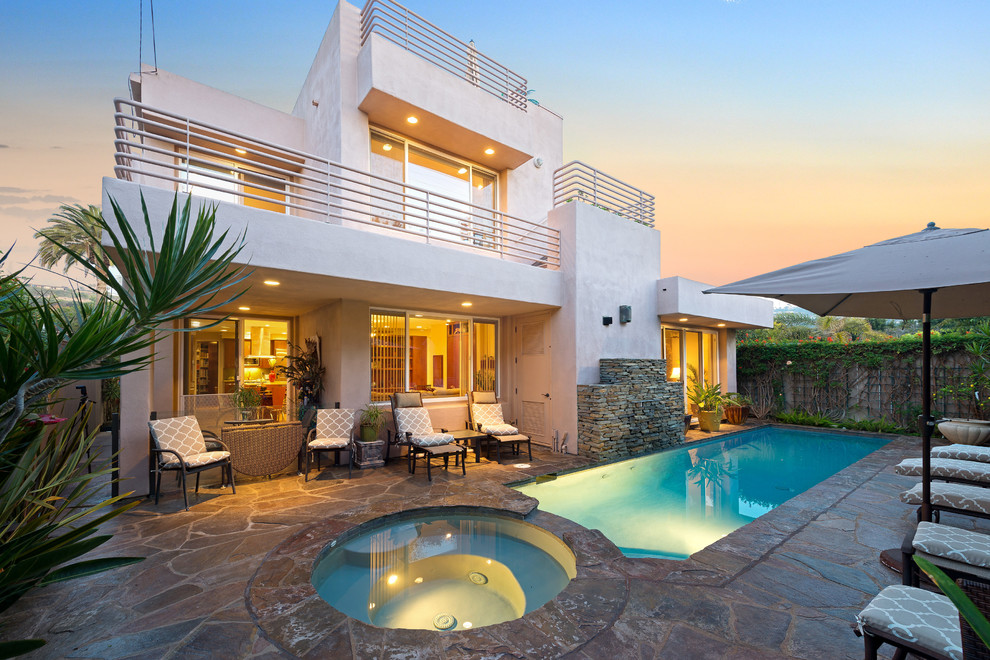 Foto di una piscina monocorsia design rettangolare di medie dimensioni e dietro casa con una vasca idromassaggio e pavimentazioni in pietra naturale