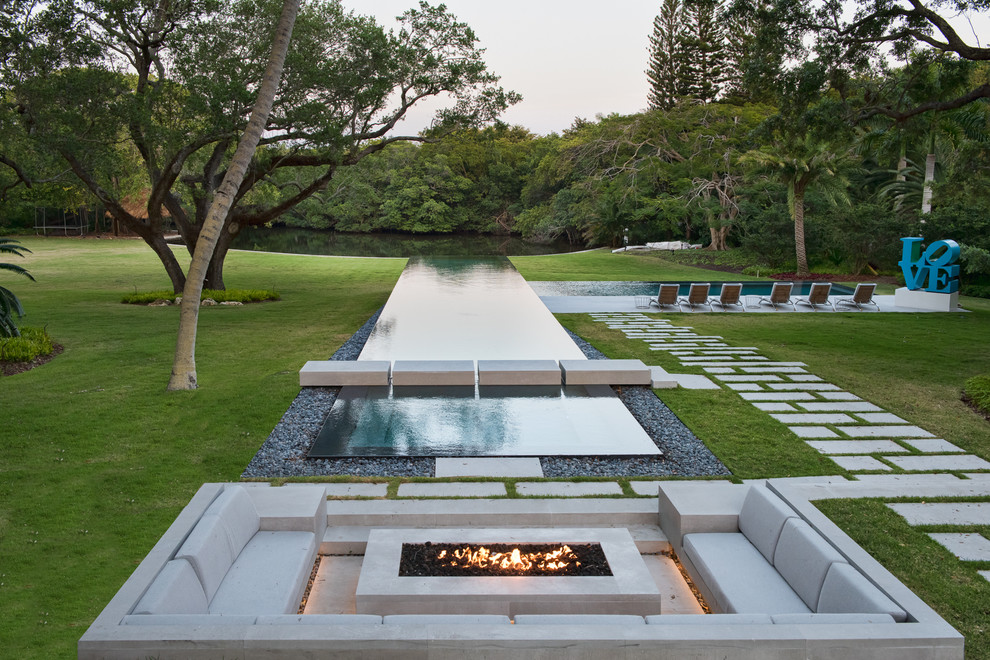 This is an example of a contemporary rectangular infinity swimming pool in Miami with gravel.
