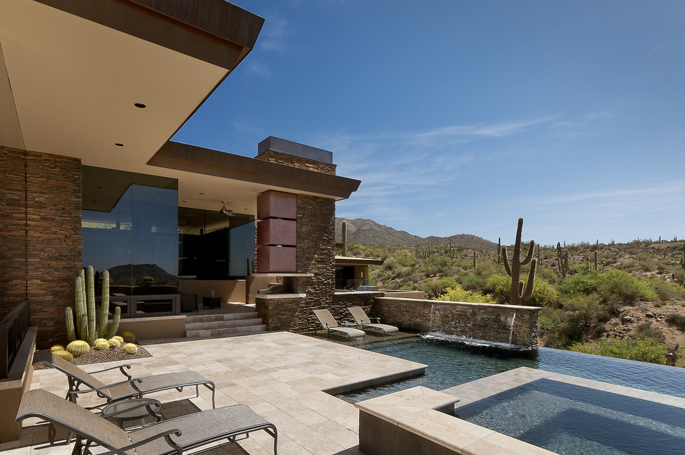 Example of a large southwest backyard custom-shaped and stone infinity hot tub design in Phoenix