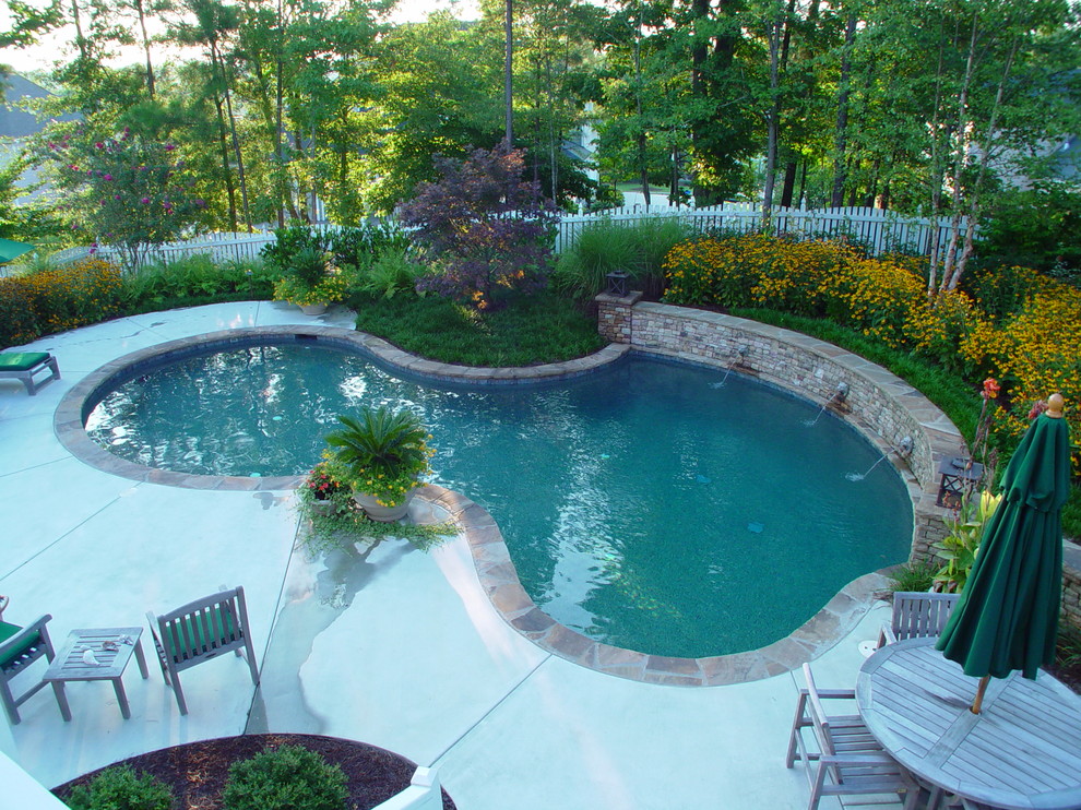 На фото: бассейн среднего размера, произвольной формы на заднем дворе в стиле рустика с фонтаном и покрытием из бетонных плит