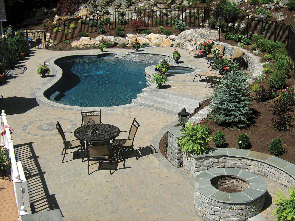 Modelo de piscina alargada tradicional de tamaño medio a medida en patio trasero con adoquines de ladrillo