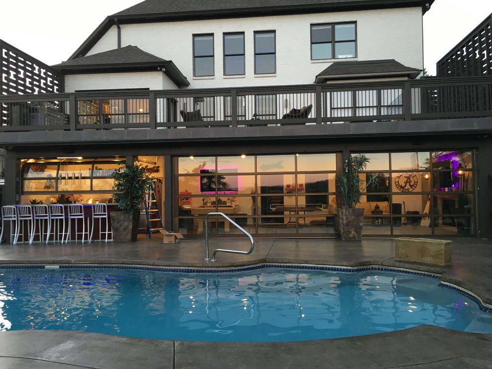 Ejemplo de casa de la piscina y piscina contemporánea extra grande rectangular en patio trasero con losas de hormigón