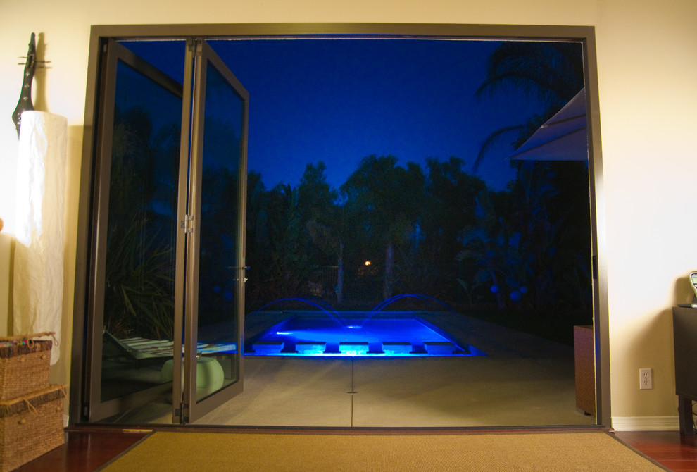 Imagen de piscina con fuente natural exótica rectangular en patio trasero