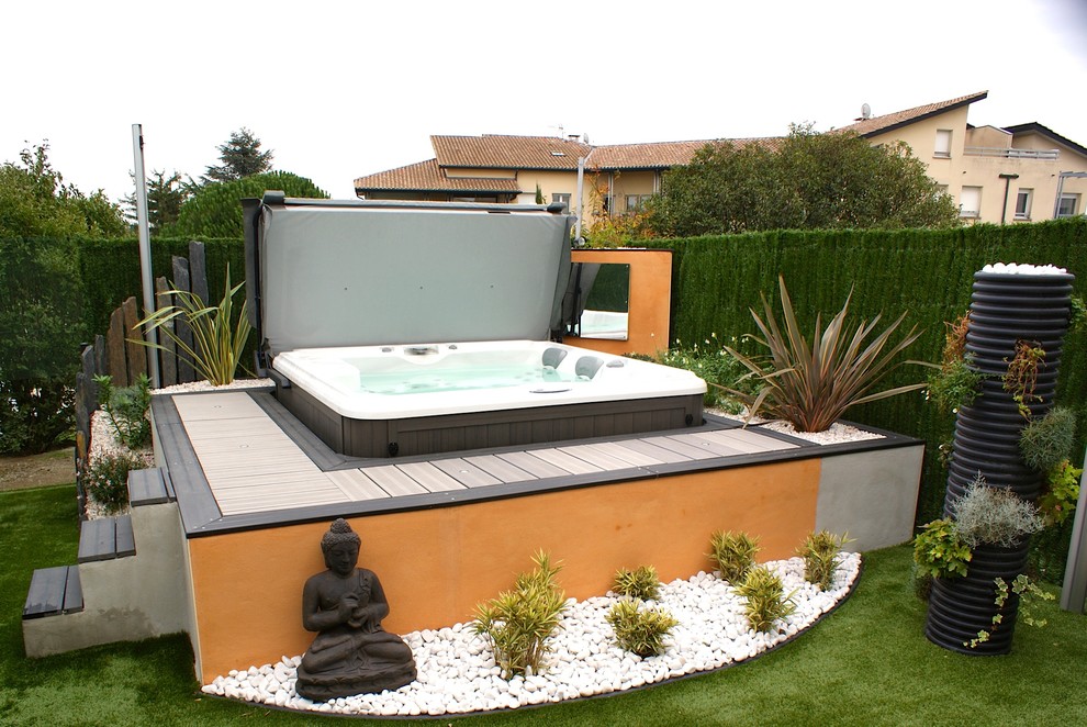 Aménagement d'une petite piscine arrière et hors-sol exotique rectangle avec un bain bouillonnant et une terrasse en bois.