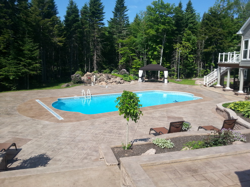 На фото: бассейн произвольной формы на заднем дворе в стиле кантри с покрытием из декоративного бетона с