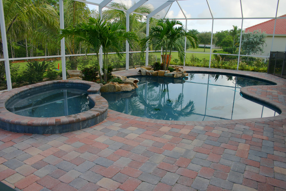 Esempio di una grande piscina tropicale personalizzata dietro casa con una vasca idromassaggio e pavimentazioni in mattoni