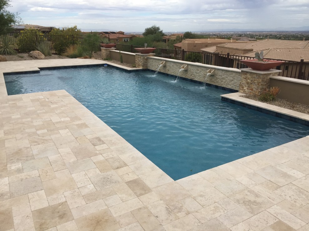 This is an example of a medium sized traditional back rectangular lengths swimming pool in Phoenix with a water feature and natural stone paving.