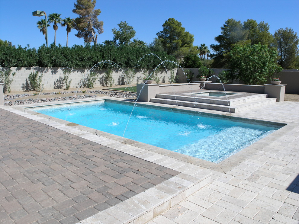 Ejemplo de piscinas y jacuzzis alargados tradicionales de tamaño medio rectangulares en patio trasero con adoquines de ladrillo
