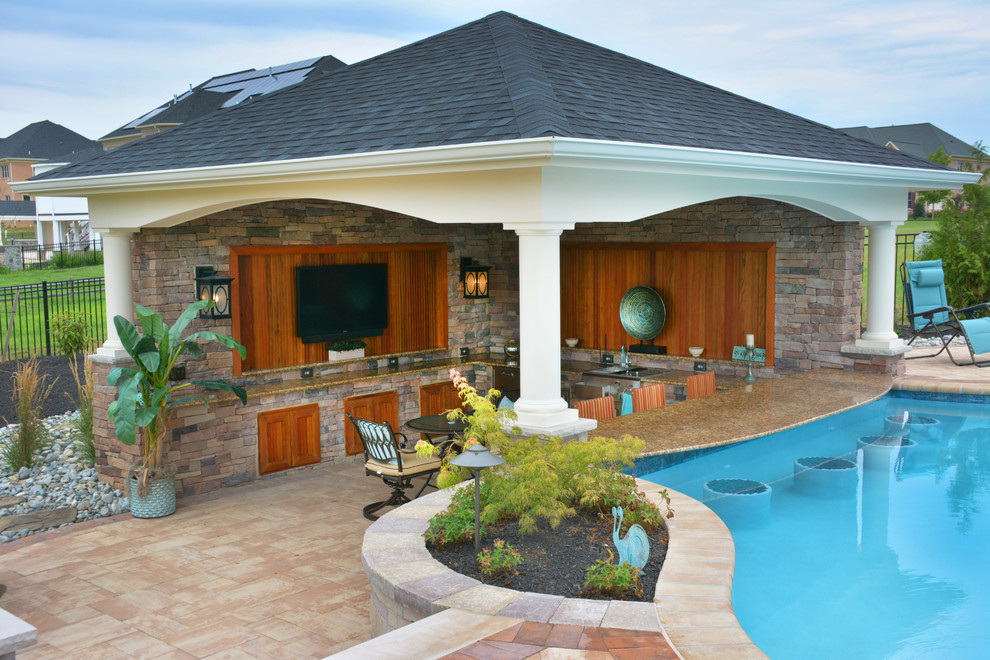 Modelo de casa de la piscina y piscina de tamaño medio a medida en patio trasero con adoquines de hormigón