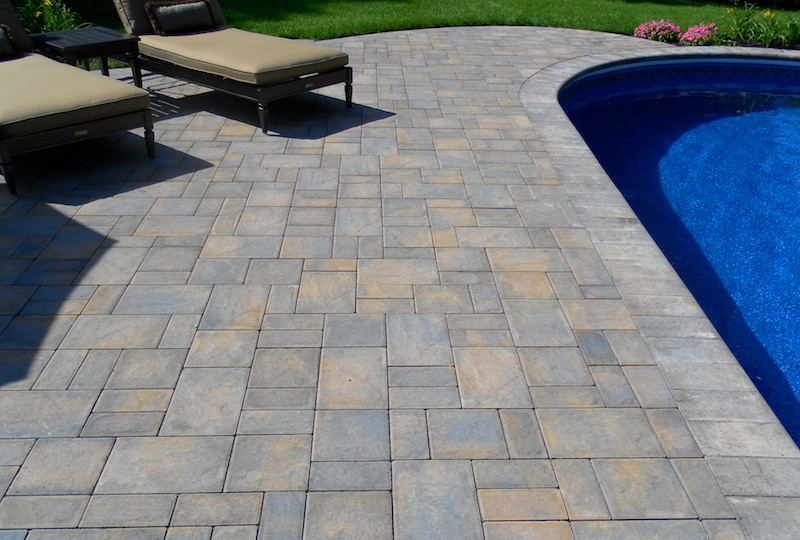 Example of a trendy concrete paver pool design in New York