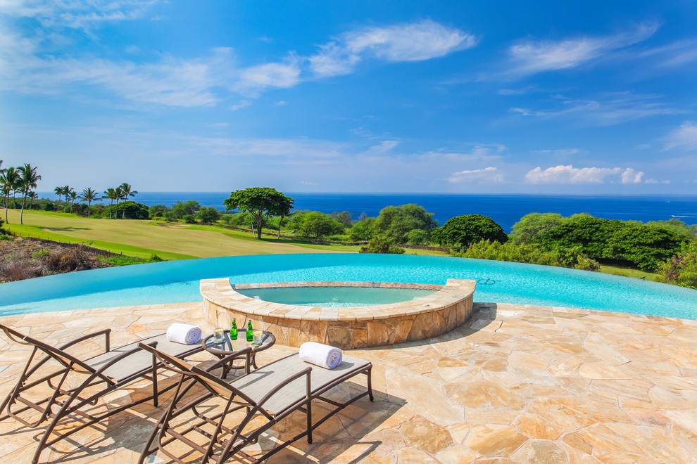 Idee per un'ampia piscina a sfioro infinito tropicale personalizzata dietro casa con una vasca idromassaggio e pavimentazioni in pietra naturale