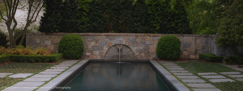 Ejemplo de piscina con fuente alargada tradicional grande rectangular en patio trasero con adoquines de piedra natural