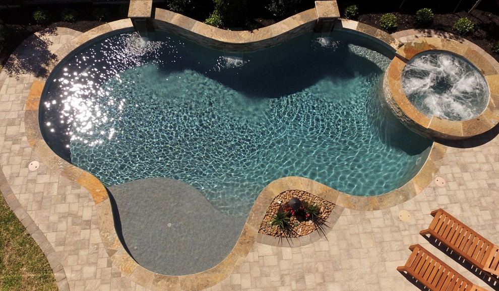 Ispirazione per una piscina classica personalizzata di medie dimensioni e dietro casa con una vasca idromassaggio e pavimentazioni in cemento