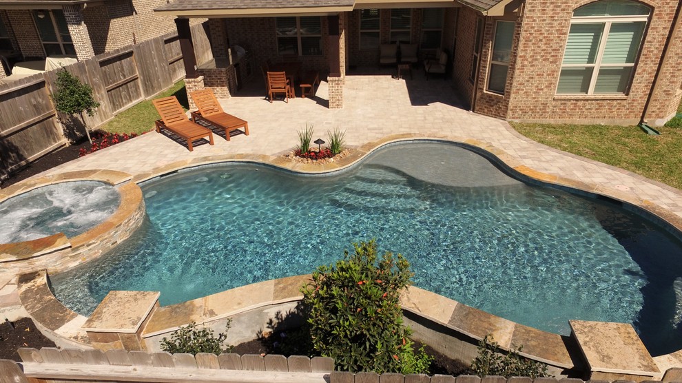 Ispirazione per una piscina chic personalizzata di medie dimensioni e dietro casa con una vasca idromassaggio e pavimentazioni in cemento