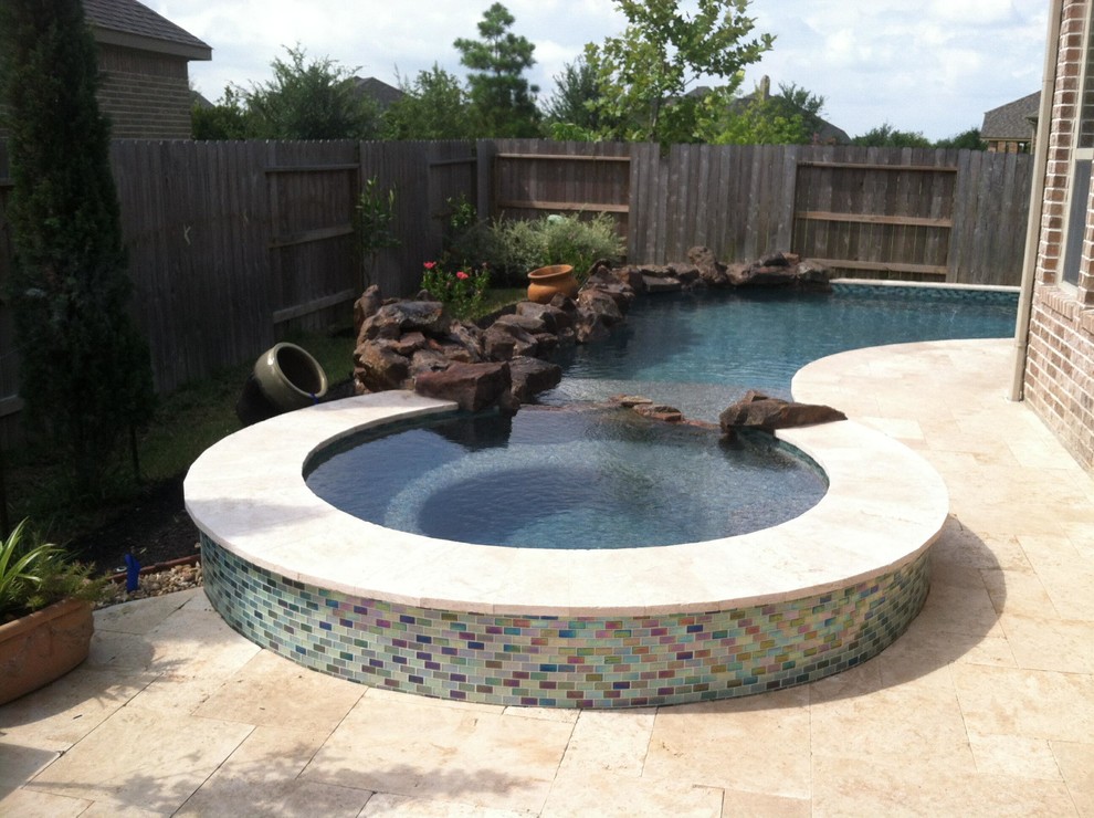Immagine di una piscina stile marinaro personalizzata di medie dimensioni e dietro casa con una vasca idromassaggio e pavimentazioni in pietra naturale