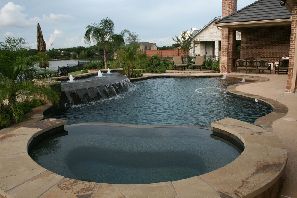 Diseño de piscina con fuente actual grande a medida en patio trasero