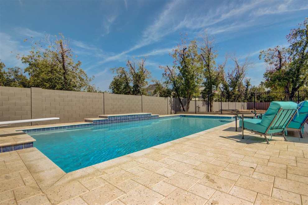 Diseño de piscina alargada clásica renovada grande rectangular en patio trasero con adoquines de piedra natural
