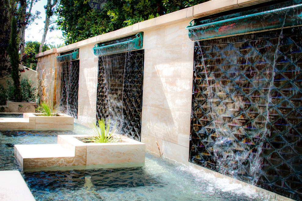 Diseño de piscina con fuente infinita minimalista grande a medida en patio trasero con adoquines de piedra natural