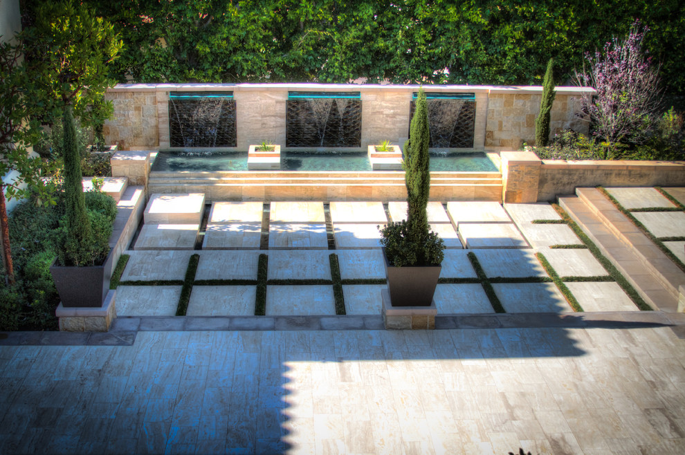 Esempio di una grande piscina a sfioro infinito moderna personalizzata dietro casa con fontane e pavimentazioni in pietra naturale