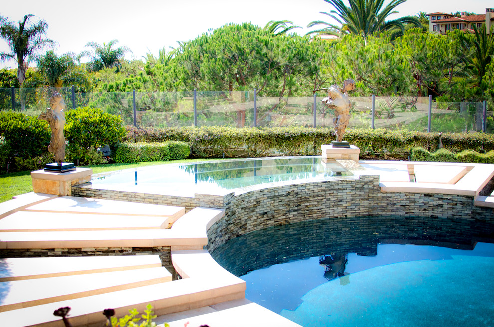 Cette photo montre une grande piscine à débordement et arrière éclectique sur mesure avec un point d'eau et des pavés en pierre naturelle.