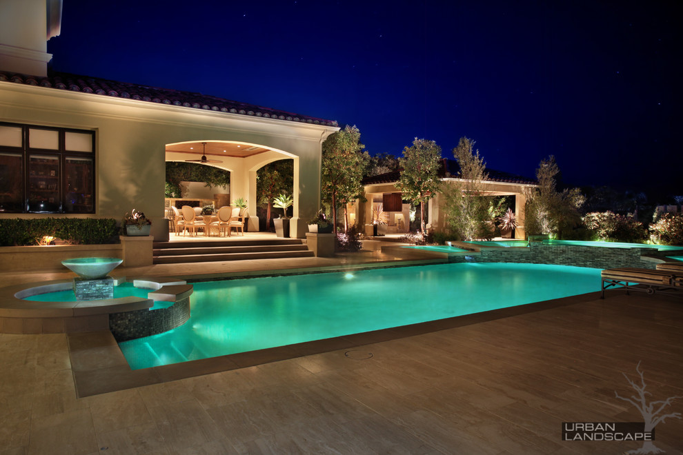 Imagen de piscina con fuente infinita tradicional grande a medida en patio trasero con adoquines de piedra natural