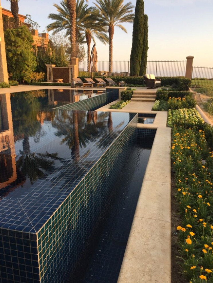 Esempio di una piscina a sfioro infinito classica dietro casa con pavimentazioni in pietra naturale