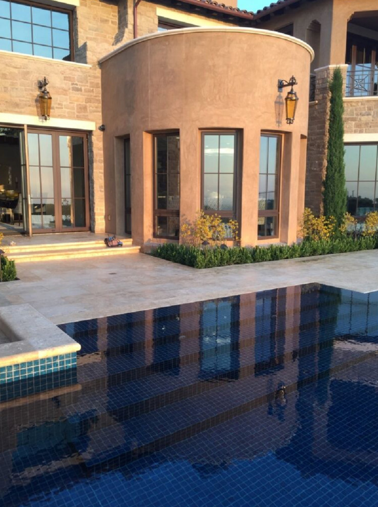 Klassischer Infinity-Pool hinter dem Haus in individueller Form mit Natursteinplatten in Orange County