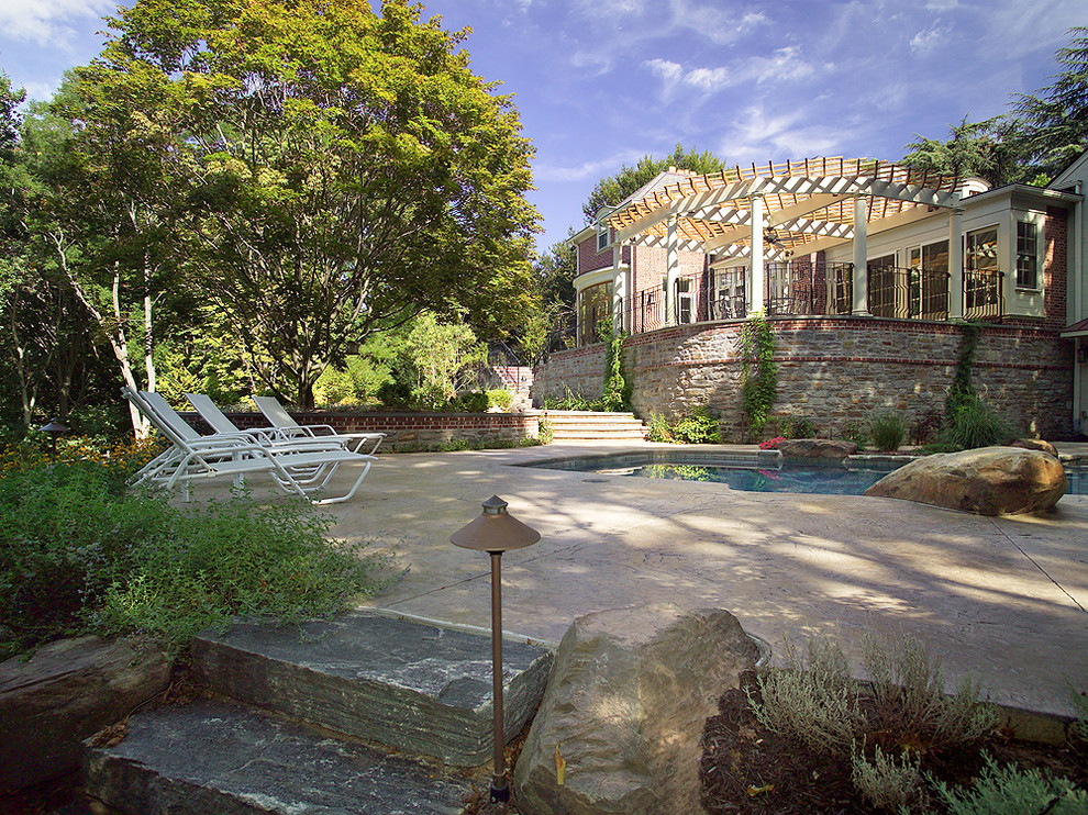 Inspiration för mellanstora klassiska pooler på baksidan av huset, med marksten i betong