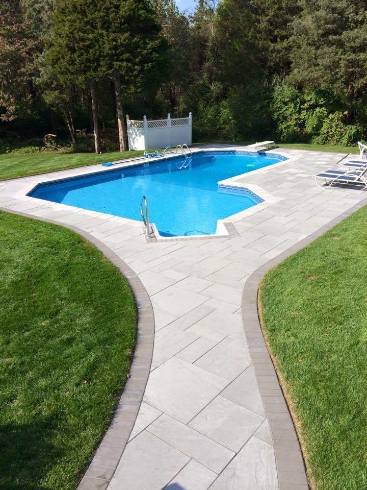 Ejemplo de piscina alargada tradicional de tamaño medio a medida en patio trasero con suelo de baldosas