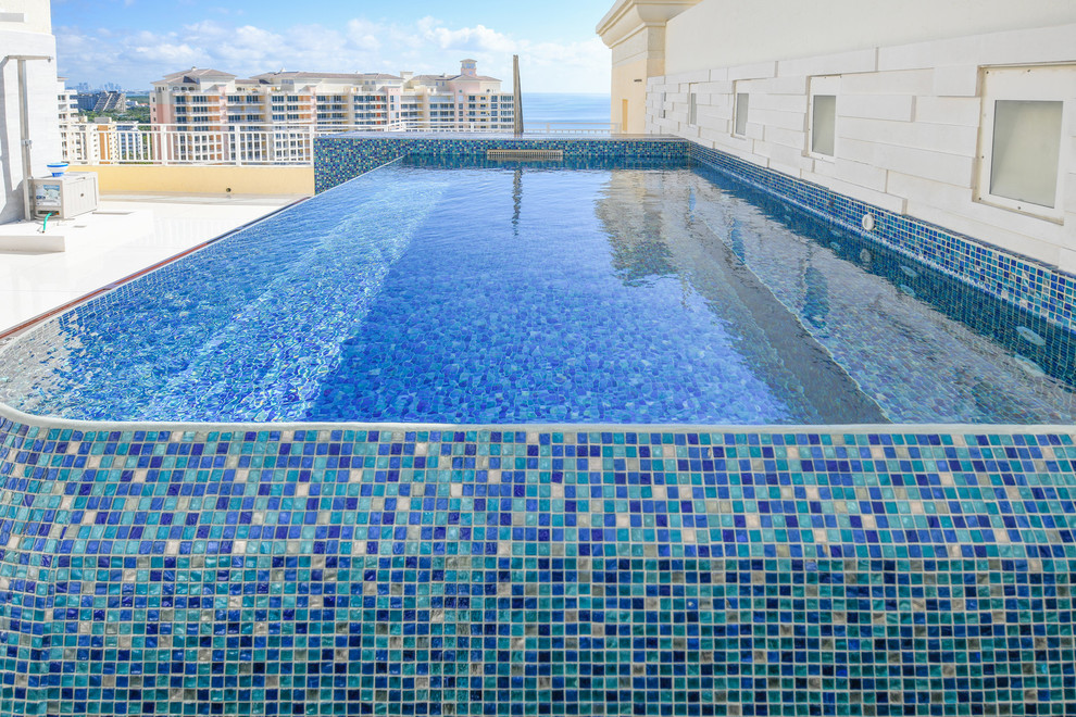 Idées déco pour une petite piscine sur toit à débordement méditerranéenne sur mesure avec un bain bouillonnant et des pavés en pierre naturelle.