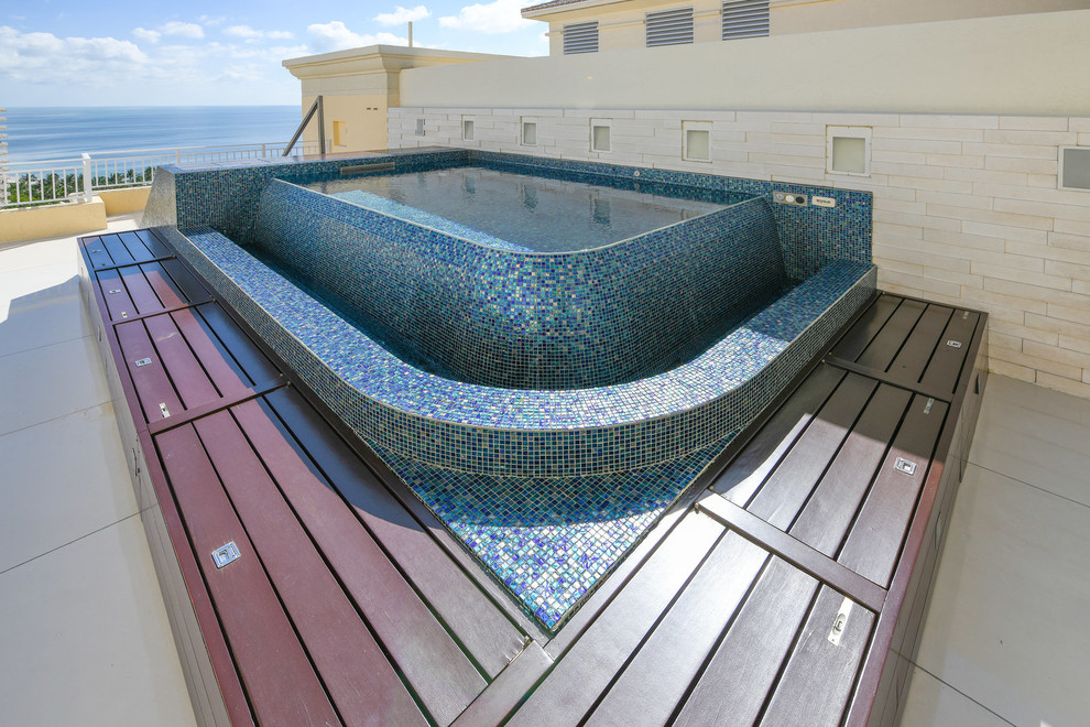 Exemple d'une petite piscine sur toit à débordement méditerranéenne sur mesure avec un bain bouillonnant et des pavés en pierre naturelle.