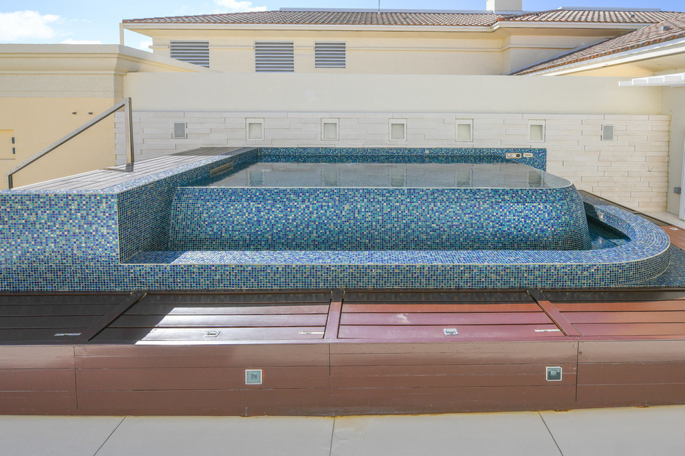 Photo of a small mediterranean roof custom shaped infinity hot tub in Other with natural stone paving.